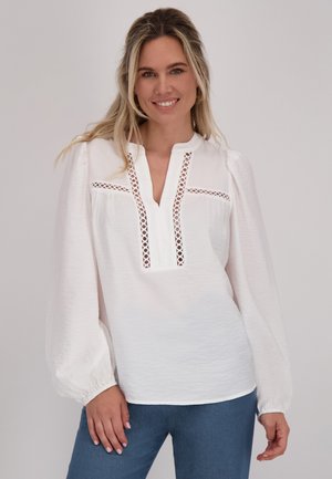 Witte blouse met lange, opgeblazen mouwen, V-hals en ingewikkelde opengewerkte details op de borst en mouwen. Zacht, gestructureerd materiaal.