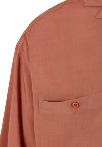 Camicia color ruggine con una trama liscia, maniche lunghe, taschino sul petto e chiusura con un solo bottone. Presenta cuciture curate e un colletto classico.