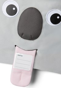 Character-shaped bag made of grey fabric, featuring large eyes and a gray snout. Includes a pink label holder for identification.