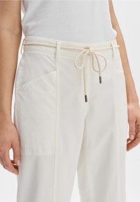 Witte katoenen broek van een katoenmix met een tailleband met trekkoord en metalen punten, zijzakken en een rechte snit. Glad textuur met minimale naden.