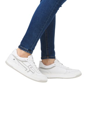 Baskets de sport blanches avec des détails texturés, des accents gris et une semelle en caoutchouc. Les lacets sont serrés, présentés sur un pied portant un jean bleu.