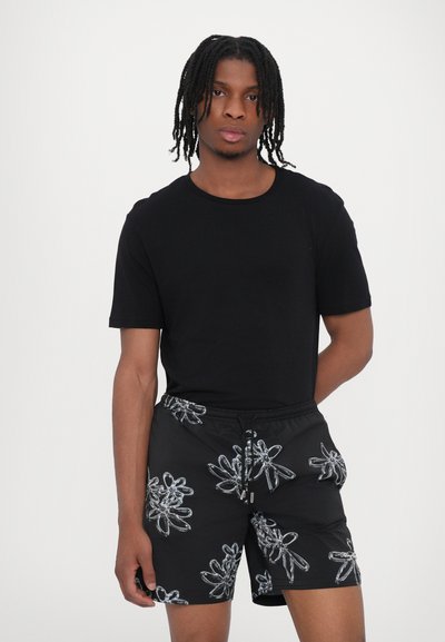 Schwarzes Kurzarm-T-Shirt kombiniert mit schwarzen Shorts mit einem glänzenden Blumenmuster, elastischem Bund und Kordelzugdetails.