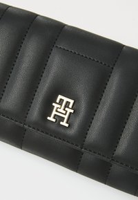 Black leather wallet featuring a quilted design and gold-tone logo hardware. The surface has a smooth texture with visible stitching accents.