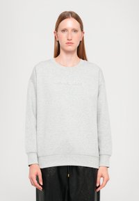 Šedá mikina vyrobená z mäkkej látky, s okrúhlym výstrihom a spustenými ramenami. Názov značky "MICHAEL KORS" je vyrazený na prednej strane.