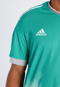 Adidas träningströja i turkos, med en strukturerad tyg, korta ärmar och grå accent vid ärmänden. Vit logotyp på bröstet.