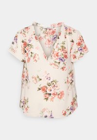 Blusa floreale con scollatura a V, maniche corte e uno sfondo beige chiaro. Presenta motivi floreali multicolori in rosa, viola e verde.