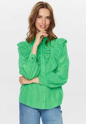 Cămașă verde cu nasturi, având accente volă pe față și umeri, cu mâneci lungi și o croială lejeră. Textura materialului este moale.