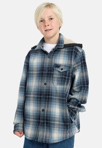 Camicia di flanella a quadri blu e bianca con bottone frontale, tasca sul petto e cappuccio foderato in pile grigio. Tessuto morbido, vestibilità ampia.