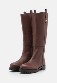 Brown leather knee-high boots with a smooth texture, rounded toe, and a durable black rubber sole. Features side zippers and pull tabs.