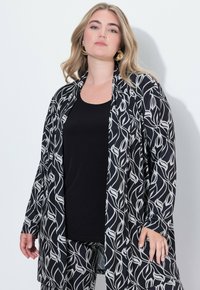 Černobílý kimono s květinovým vzorem, nošené přes černý tílko, s dlouhými rukávy a otevřeným předním dielom.