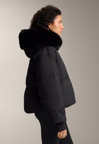 Čierna prešívaná bunda s umelým kožušinkovým golierom, s prešívaným dizajnom a voľným strihom. Bunda má rebrované manžety a kapucňu.