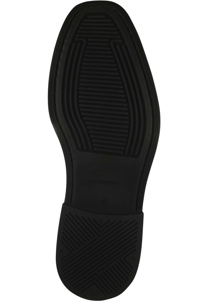 Semelle en caoutchouc noir avec une surface texturée ; présente des motifs linéaires et une étiquette embossée "GANT" avec la taille "42" au dessous.