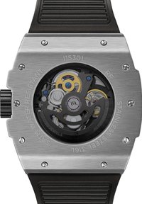 Boîtier en acier inoxydable avec un fond transparent révélant le mouvement mécanique. Bracelet en caoutchouc noir. Accents argentés, dorés et bleus sur les engrenages.