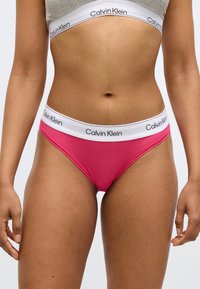 Ružové bavlnené nohavičky s bielym elastickým pásom s logom "Calvin Klein". Hladká text�úra, nízky pás a dizajn s minimálnym prekrytím.