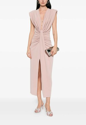 Donna con vestito rosa pallido senza maniche, scollo a V profondo, arricciato sul davanti, spacco anteriore, con borsa clutch metallica e sandali con tacco alto.