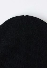 Bonnet en tricot noir avec une texture côtelée, de forme arrondie et un sommet sans couture. Le matériau semble doux et chaud, adapté aux temps froids.