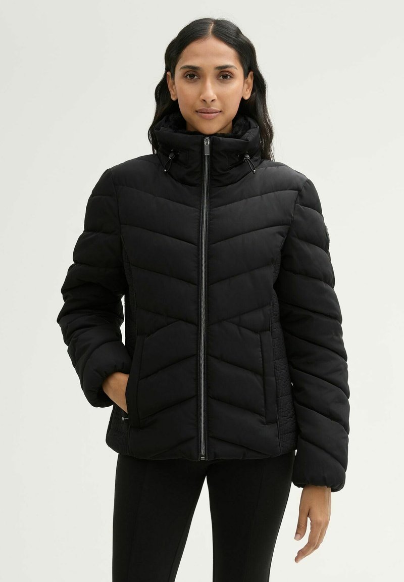 Doudoune noire avec col haut, design matelassé et fermeture éclair. Dispose de poches latérales et d'une texture douce, adaptée aux temps froids.