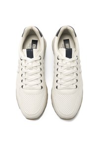 Zapatillas blancas de cuero con detalles perforados, cordones planos y acentos negros en la lengüeta. Diseño simple y aerodinámico.