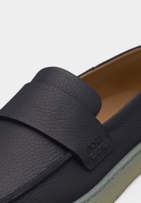 Σκούρο μπλε μοκασίνι από δέρμα με υφή και φαρδύ λουρί στο μπροστινό μέρος, με ταμπά εσωτερική επένδυση.