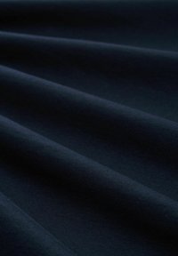 Tamsiai mėlyna medžiaga su lygiu paviršiumi, kuriame matyti švelniai banguojančios klostės. Medžiaga atrodo minkšta ir lengva, tinkama įvairiam naudojimui.