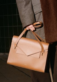 Borsa a mano in pelle color cuoio con design strutturato, dotata di chiusura a patta piegata, manici doppi e dettagli in metallo dorato.