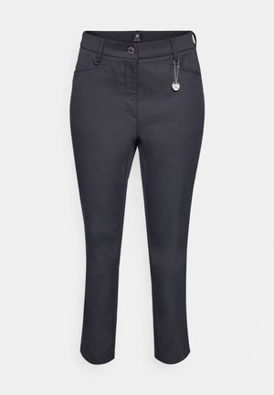 Pantalones azul marino oscuros de corte slim, con cierre de botón, bolsillos laterales y un charm decorativo adherido a la trabilla del cinturón.