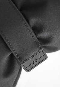 Schwarze Stofftasche mit strukturiertem Oberflächen, ausgestattet mit einem schwarzen rechteckigen Etikett, das mit "re" geprägt ist, und stabilen Seitennähten.