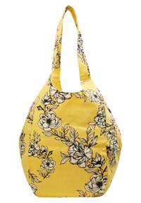 Borsa di stoffa gialla con motivi floreali neri, forma arrotondata e due manici lunghi e larghi per il trasporto. Texture morbida e design spazioso.