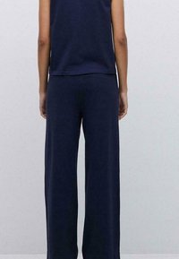 Top azul marino y pantalones de pierna ancha hechos de tejido suave. Presenta un corte relajado con un escote sencillo y sin patrones visibles.