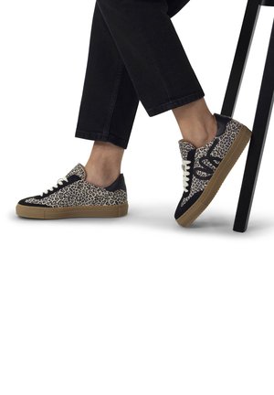 Des baskets avec un design à imprimé léopard, des accents noirs, des lacets blancs et une semelle en gomme. Le matériau semble texturé, complétant des pantalons noirs décontractés.