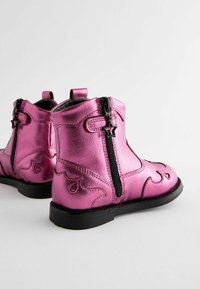 Rosa metallische Stiefeletten mit Reißverschluss. Verfügt über dekorative Nähte und sternförmige Beschläge. Glatte Textur mit glänzender Oberfläche.