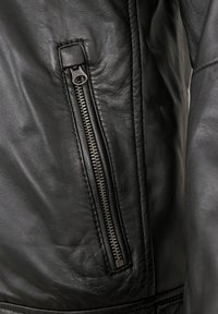 Schwarze Lederjacke mit seitlicher Reißverschlusstasche und metallischen Reißverschlussdetails; glatte Textur und taillierte Linien, die das Design betonen.