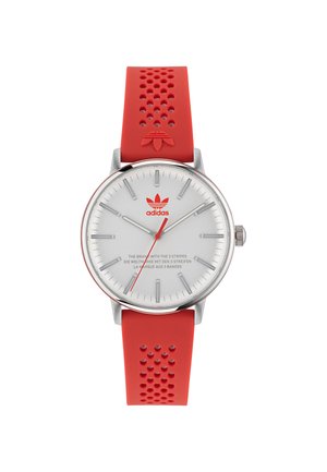 Montre bracelet en argent avec un cadran blanc, des accents rouges et un bracelet en silicone perforé rouge. Présente du matériel en argent poli et des index marquants.