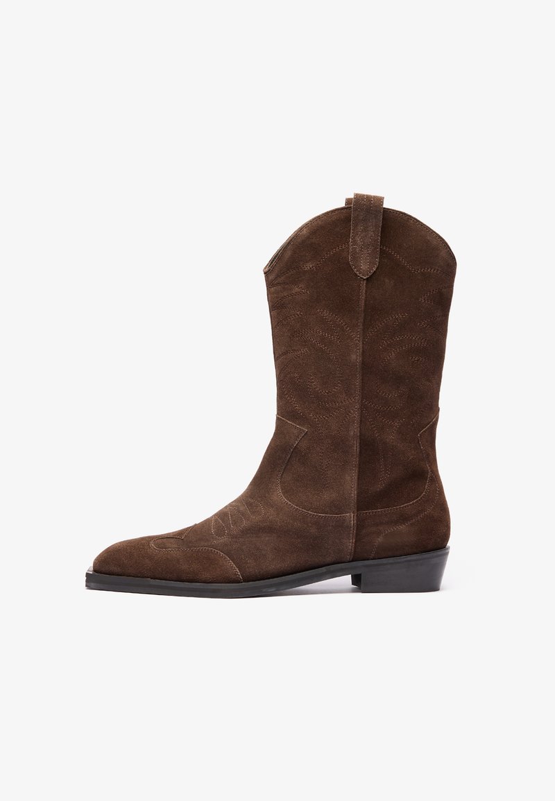 Bota vaquera de ante marrón con punta afilada, detalles de costura grabada y un tacón bajo en forma de bloque. Cuenta con pestañas laterales para facilitar su uso.