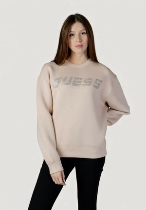 Sweat-shirt rose clair avec un col rond et une coupe oversize, orné d'un logo "GUESS" métallique argenté sur le devant.