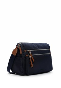 Marineblaue Stofftasche mit braunen Akzenten, die drei Reißverschlusstaschen und einen langen Trageriemen bietet. Glatte Textur mit klassischer rechteckiger Form.