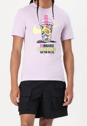 T-shirt en coton violet avec un motif graphique d'une boisson aux éléments colorés, associé à un short cargo noir à multiples poches.