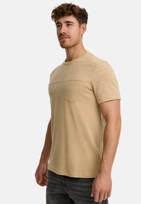 Beige kortærmet t-shirt med et struktureret overpanel, rund halsudskæring og en enkelt brystlomme. Blødt stof med en afslappet pasform.