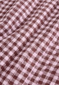 Material în carouri maro și roz cu textură țesută, având pătrate mici în culori alternative. Aspect ușor mototolit.