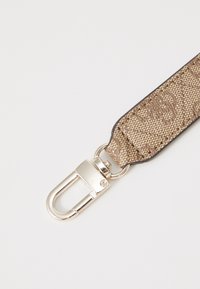 Cinghia in tessuto marrone a motivi con una texture liscia, dotata di una clip metallica argentata per l'attacco. Dettagli sui bordi in colore più scuro.
