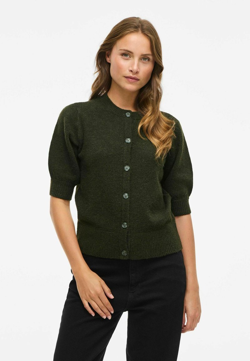 Cardigan en maille vert foncé avec de courtes manches bouffantes, un col rond et une fermeture à cinq boutons sur le devant. Tissu texturé.