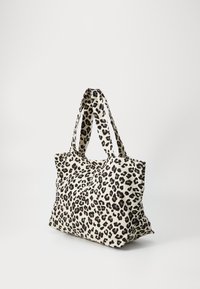 Leopard print tote bag made of fabric, featuring two sturdy handles, a spacious design, and a soft texture with an off-white background.
