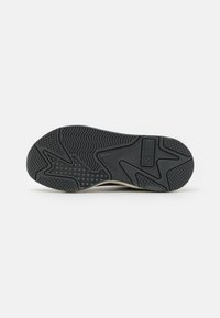 Suela de zapato de goma negra con una superficie texturizada con un patrón de ondas, acentos angulares y un detalle del logo cerca del talón.
