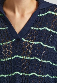 Navy blue knitted pullover with a V-neck, featuring a lace texture and green zigzag stripes. Lightweight and breathable design.
