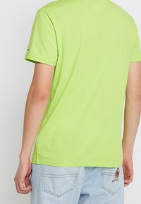 Limonkowa bawełniana koszulka z krótkim rękawem, z tyłu dekolt w subtelny kształt V. Jeansy w jasnoniebieskim kolorze z widoczną haftem.