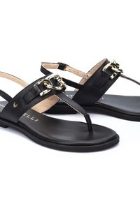 Sandalias de cuero negro con diseño de tiras, detalles en cadena dorada y suela lisa. Presenta correas ajustables en el tobillo para un ajuste seguro.
