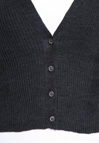 Svart ribbad cardigan med en djup V-ringning, med sex små bruna knappar framtill. Tyget har en mjuk textur.