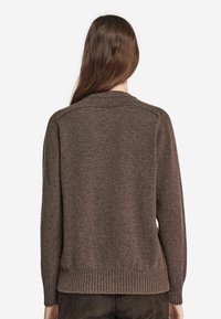 Un pull en maille marron avec un ourlet et des poignets côtelés, ayant une coupe décontractée et un tissu texturé, présenté de dos.