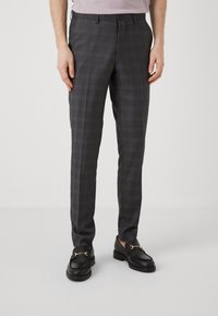 Grå rutete bukser med en skreddersydd passform, med knappelukking og beltehemper. Brukt med svarte loafers som har detaljer i gull.