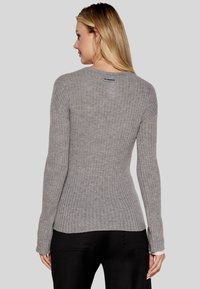 Maglione grigio a coste con maniche lunghe, design aderente e branding discreto sul colletto. Tessuto testurizzato e leggero svaso all'orlo.